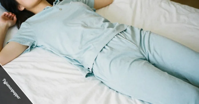 Woman wearing soft Pyjamaspapper sleepwear set in blue sitting on comfortable bed with white sheets in calm bedroom